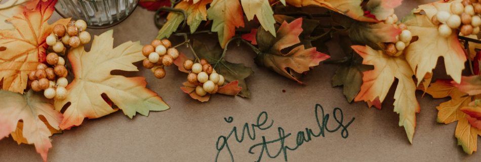 Thanksgiving table setting with autumn leaves and handwritten gratitude card