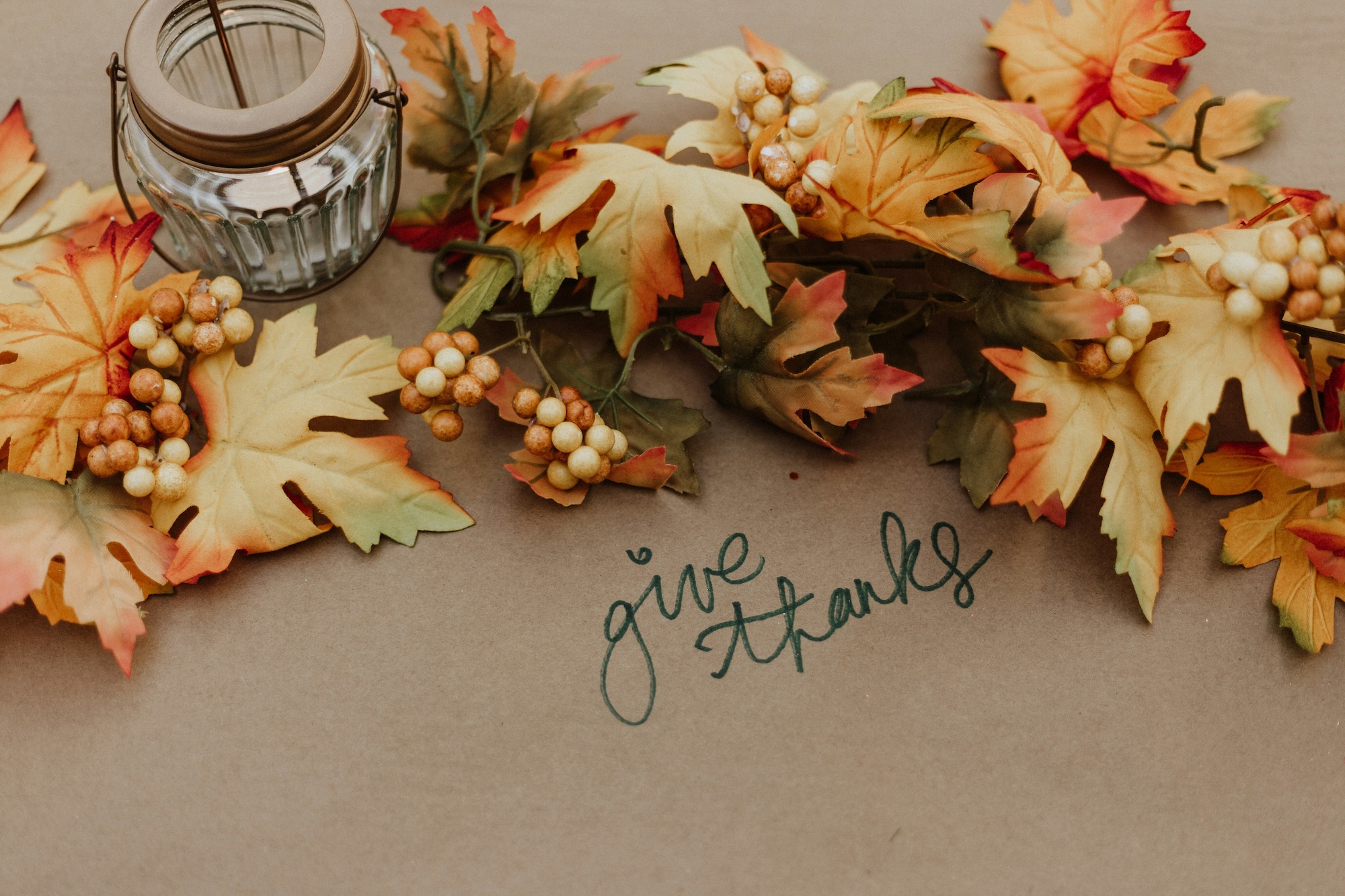 Thanksgiving table setting with autumn leaves and handwritten gratitude card